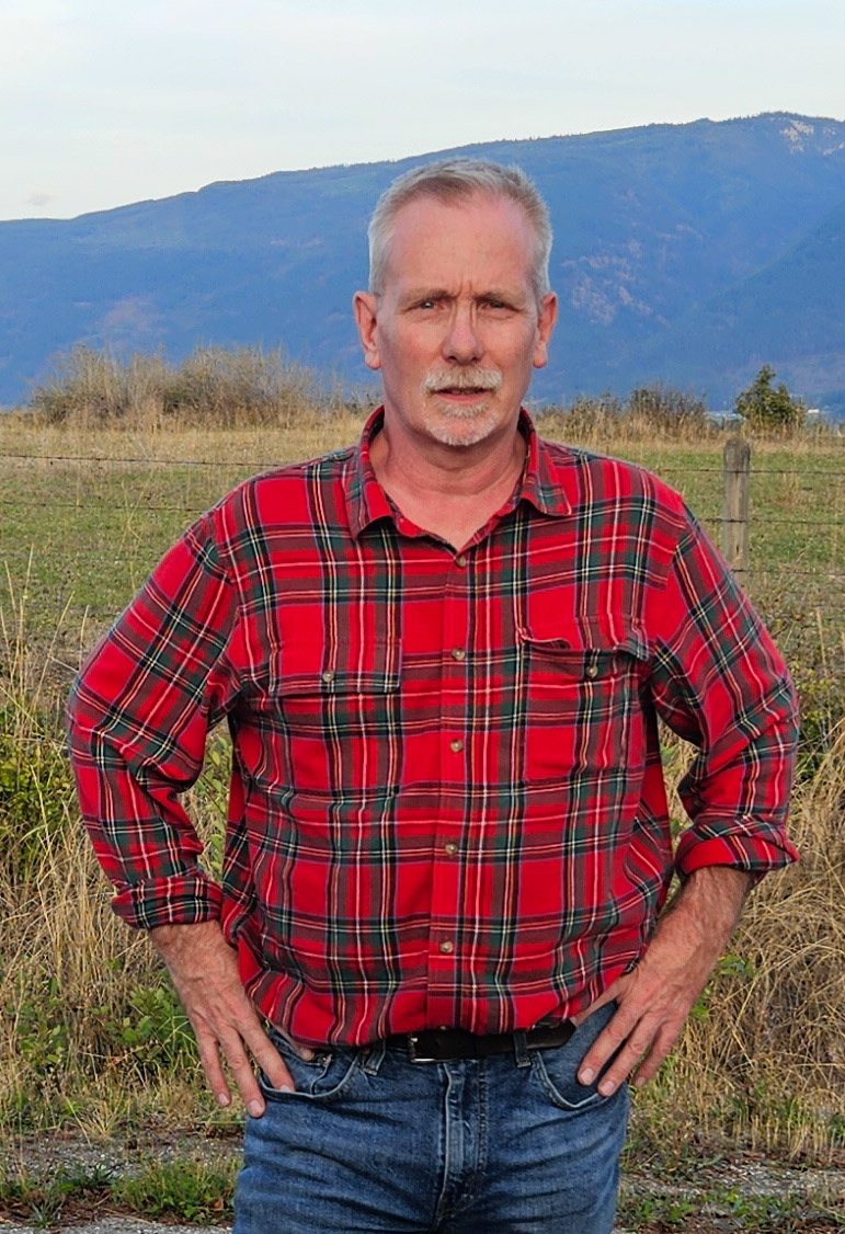 Portrait of Warren Smith standing outdoors in front of mountains